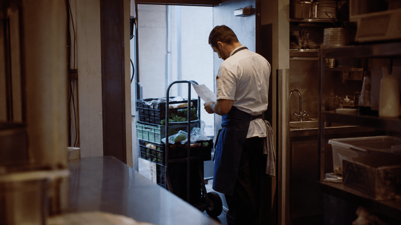 Souschef, der bei einer Lieferung an der Hintertür des Restaurants einen Lieferschein vom Fahrer annimmt