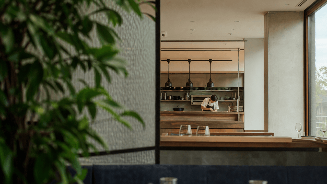 Open restaurant kitchen pass seen from the dining room, front and back of house connected by one system